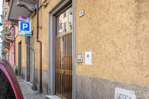 Un bâtiment avec un panneau indiquant un parking, une entrée fermée par un portail et un panneau affichant un numéro.