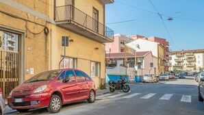 Ein rotes Auto steht auf einer Straße, im Hintergrund sind Gebäude zu sehen.