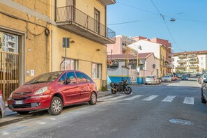 A red car parked on a street with buildings in the background.
