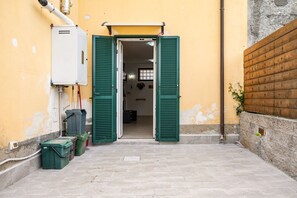An open door leading to a room with a tiled floor, a white electrical box, and green shutters on the wall.