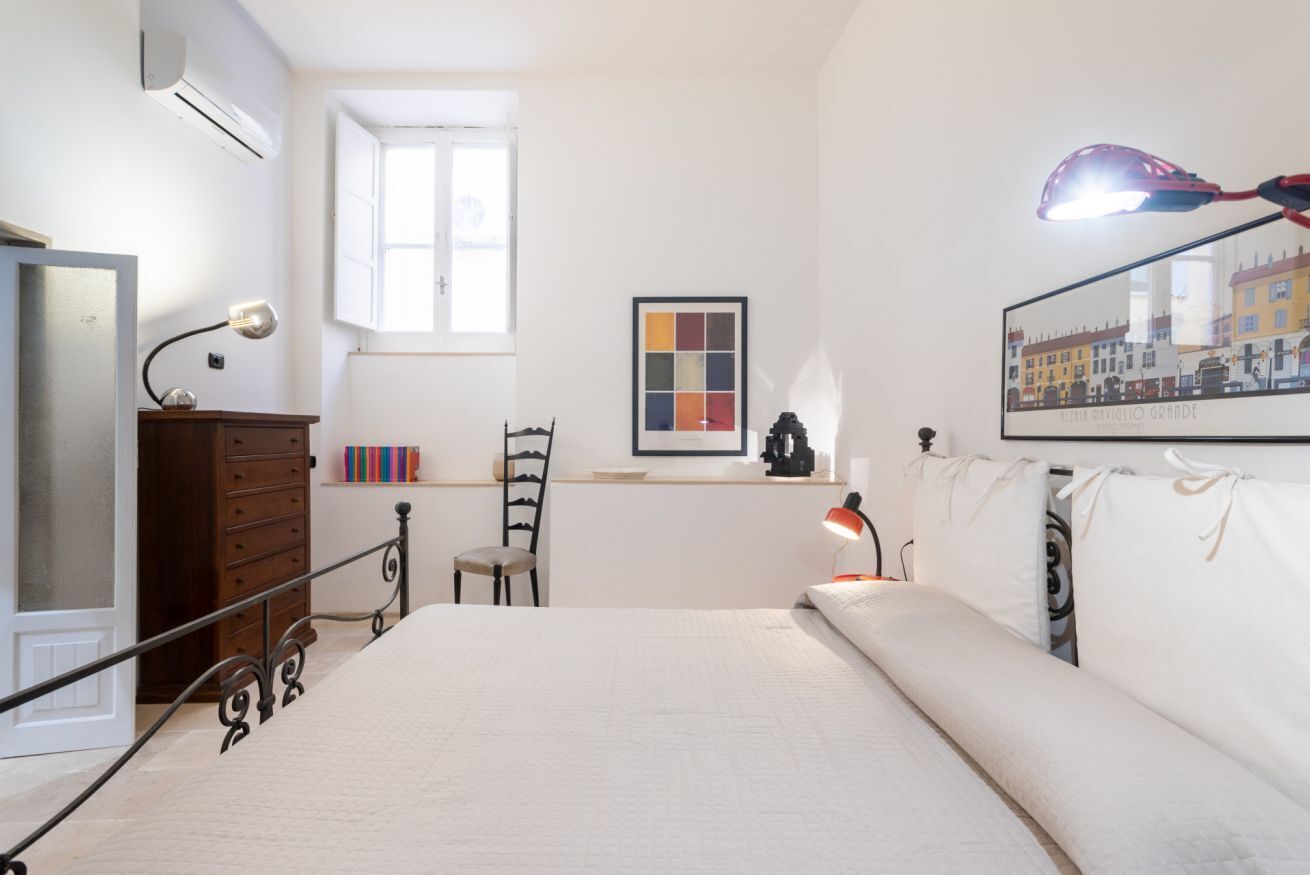 A bedroom with a bed, dresser, desk, chair, and a window.