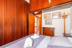 A bedroom with a bed, wooden wardrobe, a dresser, and a coat rack.