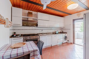 A kitchen with white cabinets, a stove, a sink, and a washing machine.