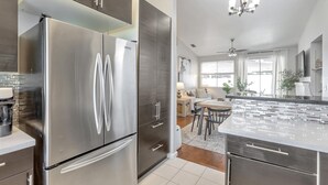 Une cuisine moderne équipée d’appareils électroménagers en acier inoxydable, un coin repas avec une table et des chaises, et un lustre.