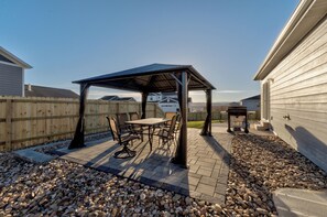 Una zona patio con un'area salotto coperta, un tavolo e delle sedie.