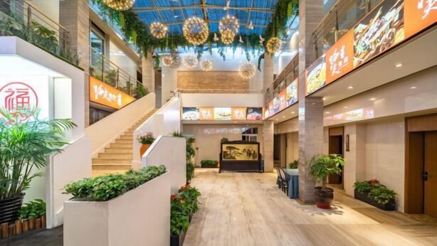 A spacious indoor area with a central staircase, potted plants, and a ceiling with hanging decorations.
