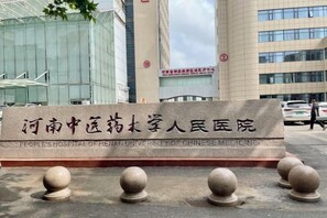 A sign for the People's Hospital of Henan University of Chinese Medicine with a modern building in the background. - Zhengzhou University Institute of Technology Hotel (Zhengzhou)