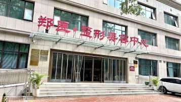 Un bâtiment orné d’une grande enseigne en caractères chinois, doté d’une entrée en verre et d’un espace pavé avec des marches menant à l’entrée.