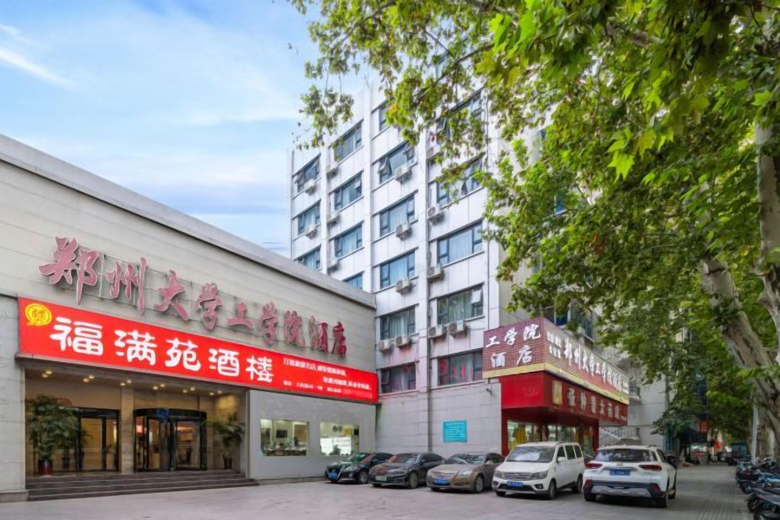Un bâtiment avec une enseigne rouge indiquant la présence d’un hôtel et d’un restaurant. Des voitures sont garées devant.