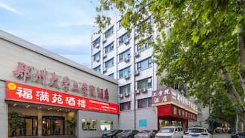A building with a red sign indicating a hotel and a restaurant. There are parked cars in front.