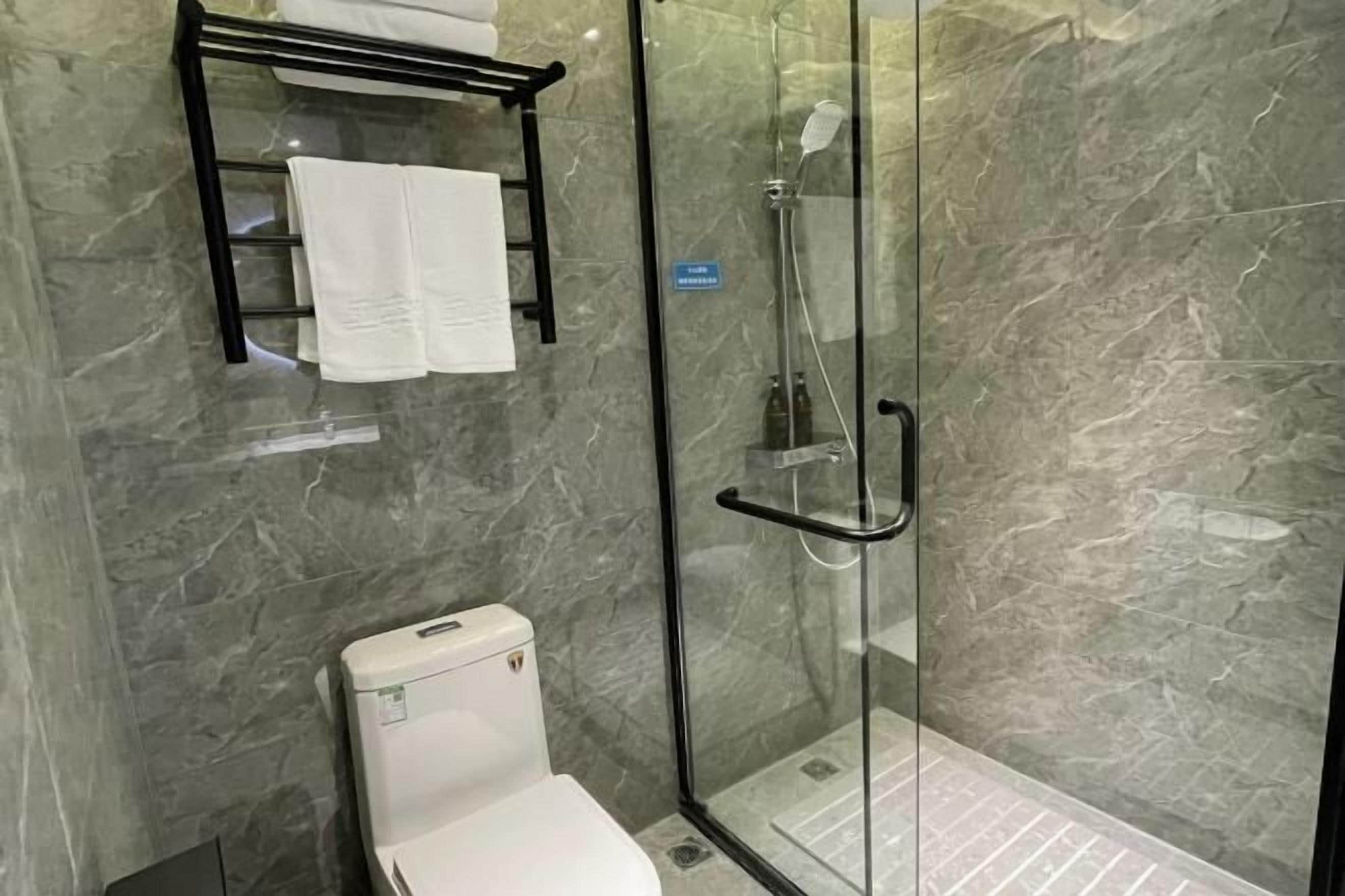 Ein modernes Badezimmer mit einer Duschkabine, einer Toilette und einem Handtuchhalter.