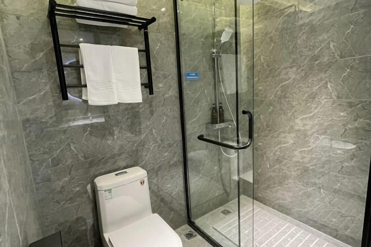 A modern bathroom with a glass-enclosed shower, a toilet, and a towel rack.