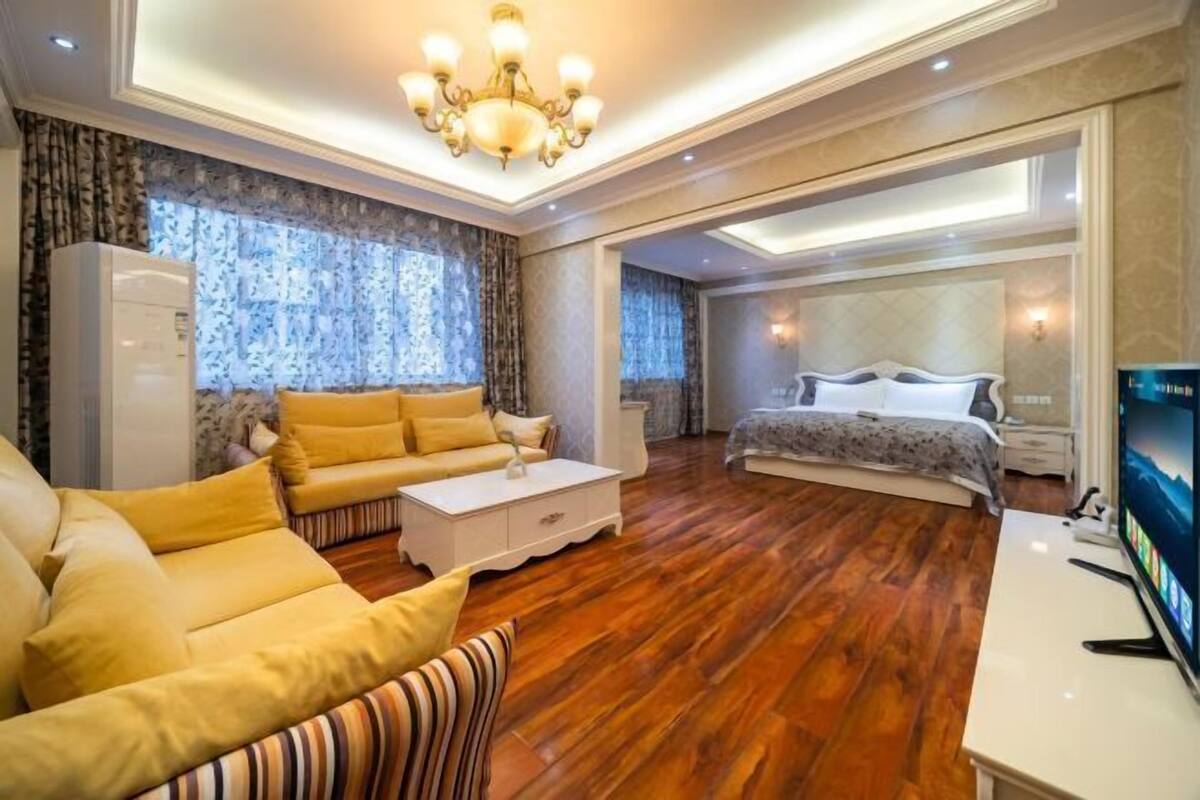Ein Hotelzimmer mit einer Couch, einem Bett, einem Fernseher und Holzboden.