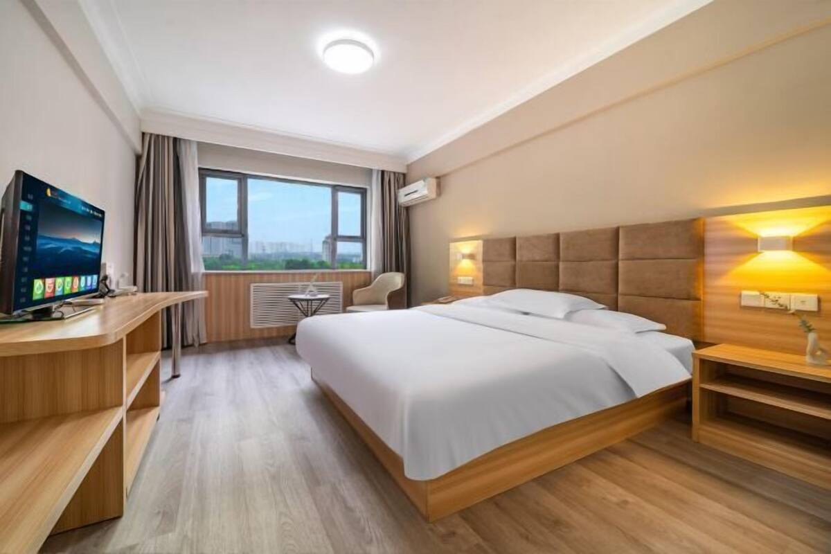 Ein Hotelzimmer mit Bett, Schreibtisch, Fernseher und Blick auf die Stadt.