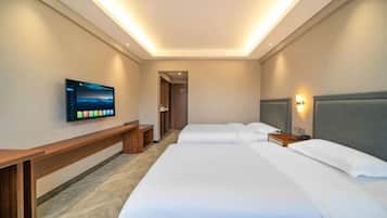 Habitación de hotel con dos camas, un televisor montado en la pared y un banco.