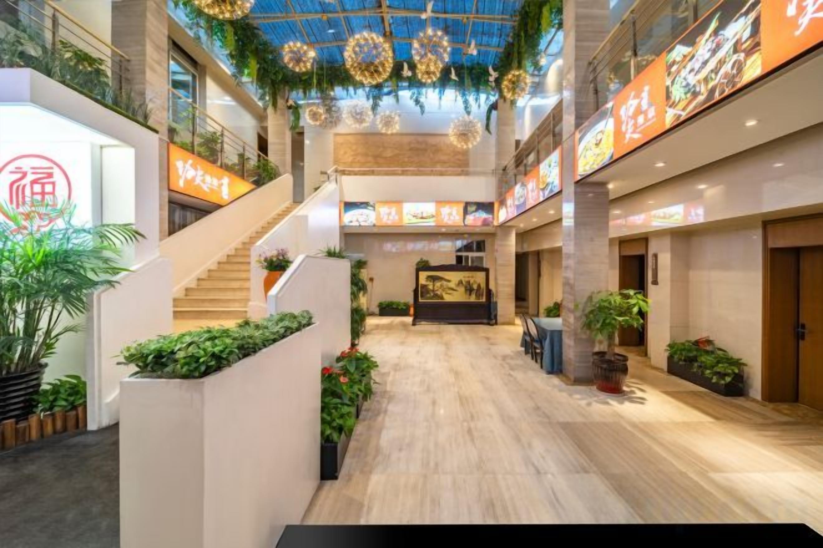 A spacious atrium with a wooden floor, a staircase, and potted plants.