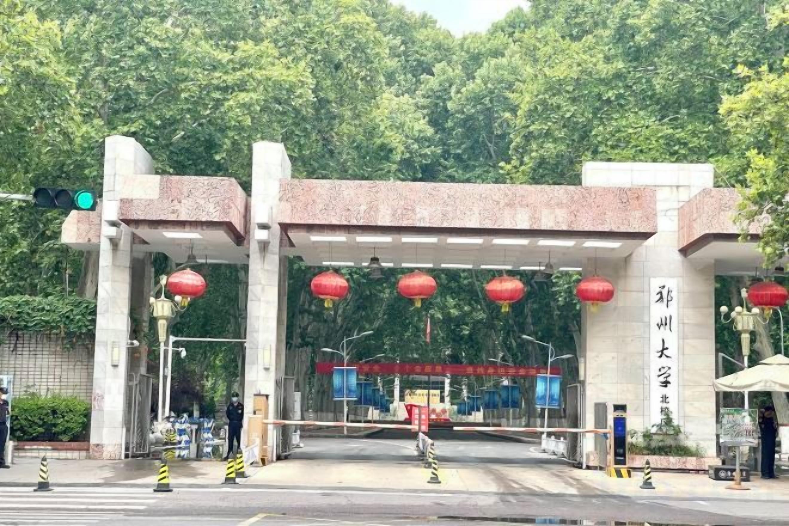 Une entrée fermée par un portail, surmontée d’une arche de style traditionnel, avec un feu de signalisation et des lanternes rouges.