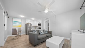 A modern living room with a grey sofa, a white coffee table, and a ceiling fan. - Central 1-Bedroom Apartment w/ Sofa Bed & Full Kitchen (Fort Lauderdale)