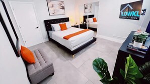 A modern bedroom with a bed, a desk, and a chair. There is a mirror on the wall and a ceiling fan. - Bright 3-Bedroom 3 Bath Apt with Pool, Parking, & Close to Beach & Las Olas (Fort Lauderdale)