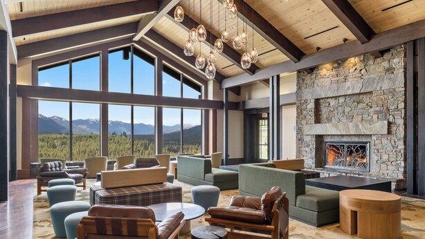 Un salón espacioso con ventanas amplias, chimenea de piedra y muebles modernos.