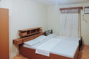 Ein Schlafzimmer mit einem Bett, Nachttischen aus Holz, einem Kleiderschrank und einem Fenster mit Vorhängen.