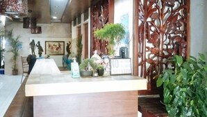 A reception area with a wooden reception desk, potted plants, and a decorative wooden partition.