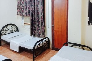 A small, single-bed room with a wooden door, a window with floral curtains, and a wall-mounted air conditioning unit. - RedDoorz @ Plaza la Paz Iloilo City (Iloilo City)