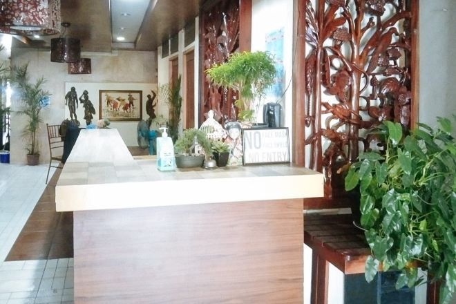 A reception area with a wooden counter, potted plants, and a decorative screen.