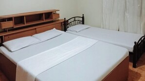 A double bed with a wooden headboard, a bedside table with drawers, and a shelf above the bed.