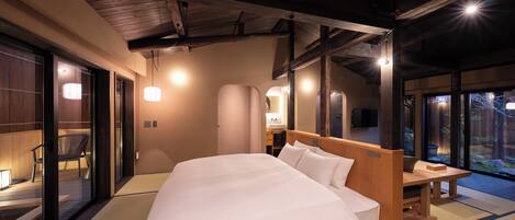 Habitación de hotel moderna con una cama grande, cabecera de madera y puertas correderas de vidrio que dan a un balcón.