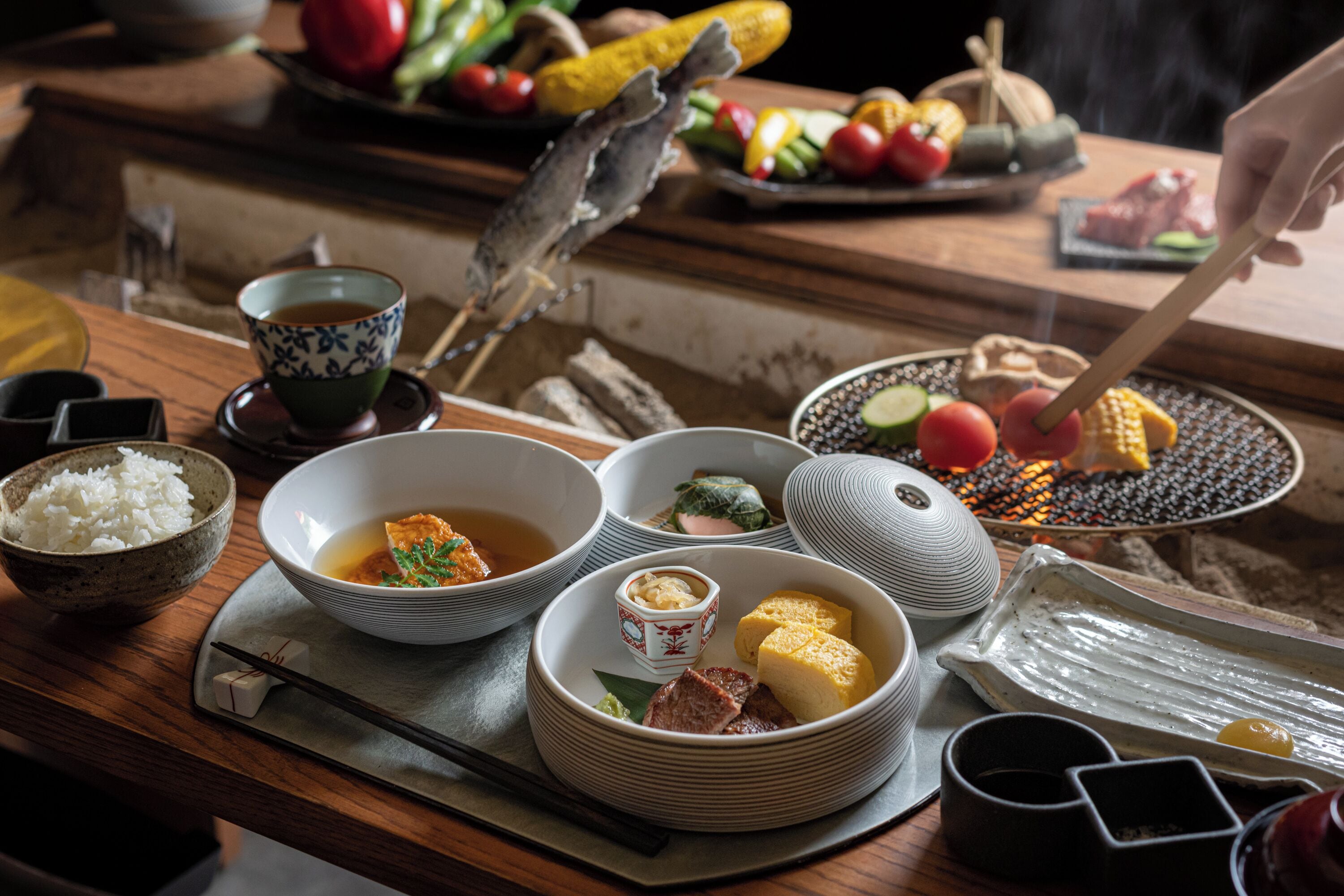 A dining table with various dishes, including bowls of soup and rice, and a plate with vegetables and meat.