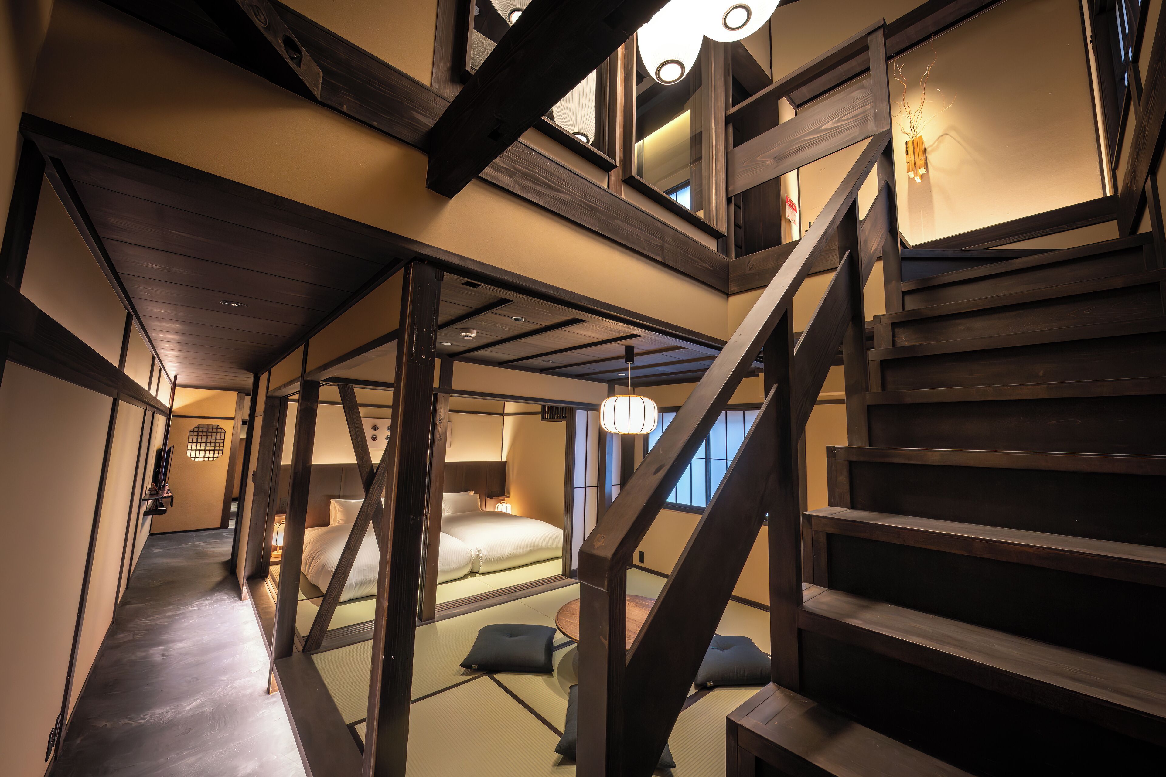 A traditional Japanese-style room with tatami flooring, a low wooden bed, and a sliding door leading to another room.
