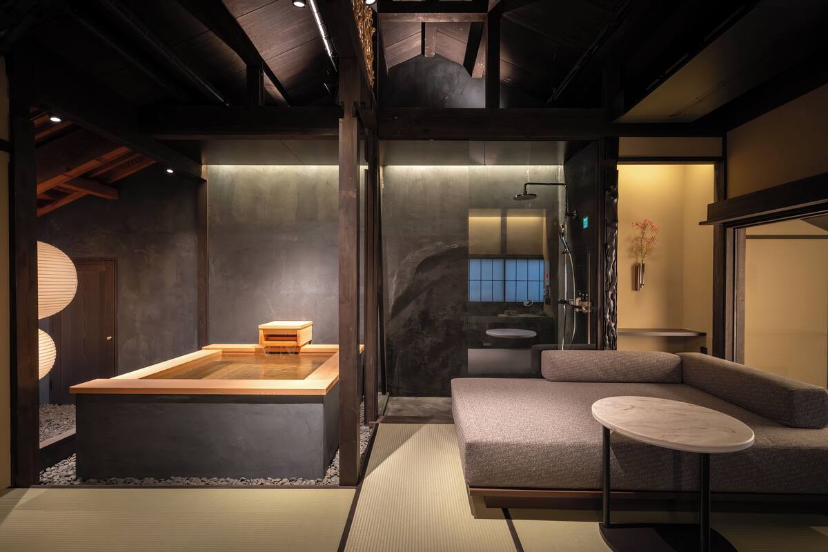 Un baño moderno con bañera, lavamanos y ducha. Hay un sofá y una mesita en la habitación.