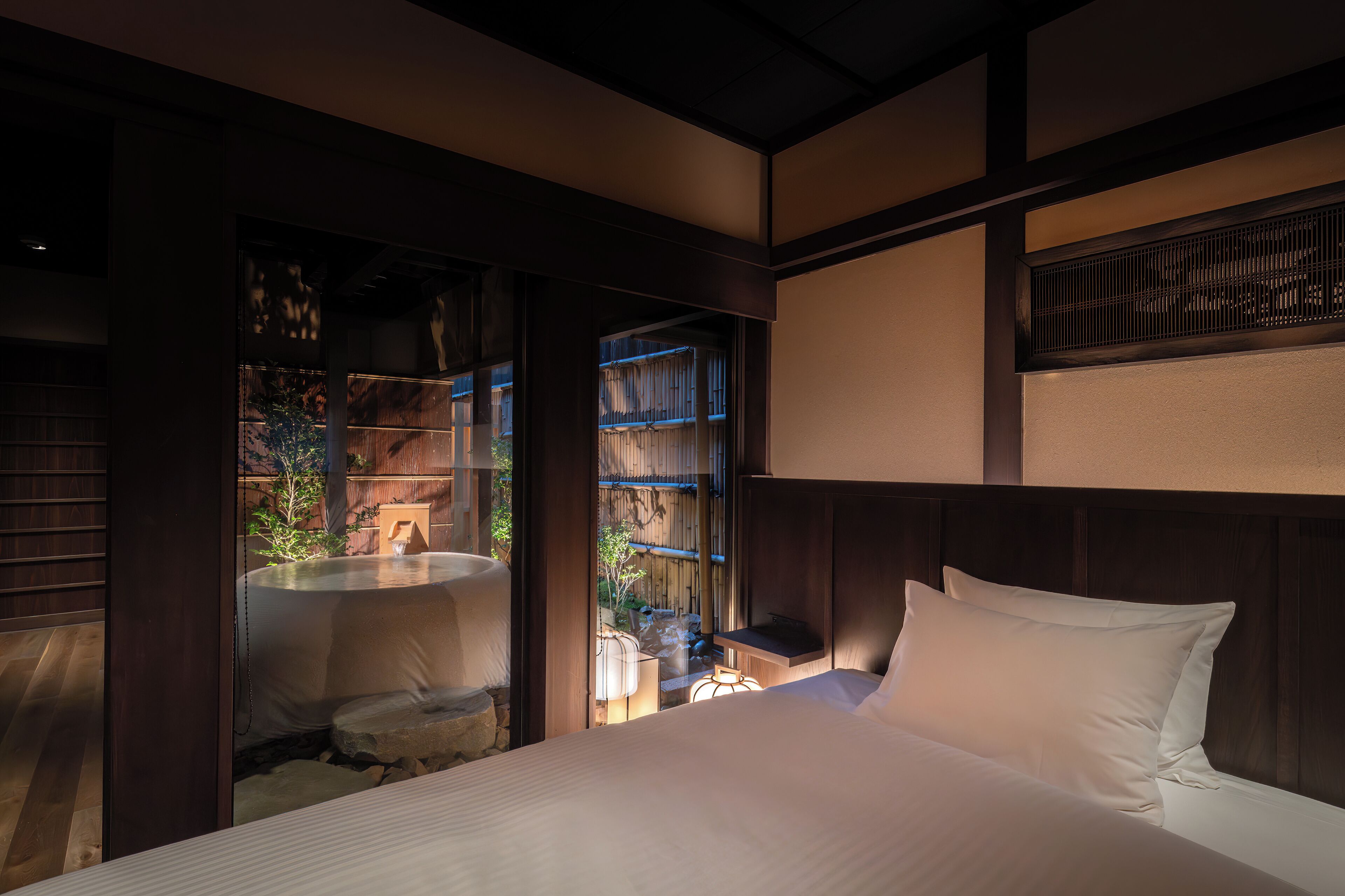 A bedroom with a bed, a small table, and a window.
