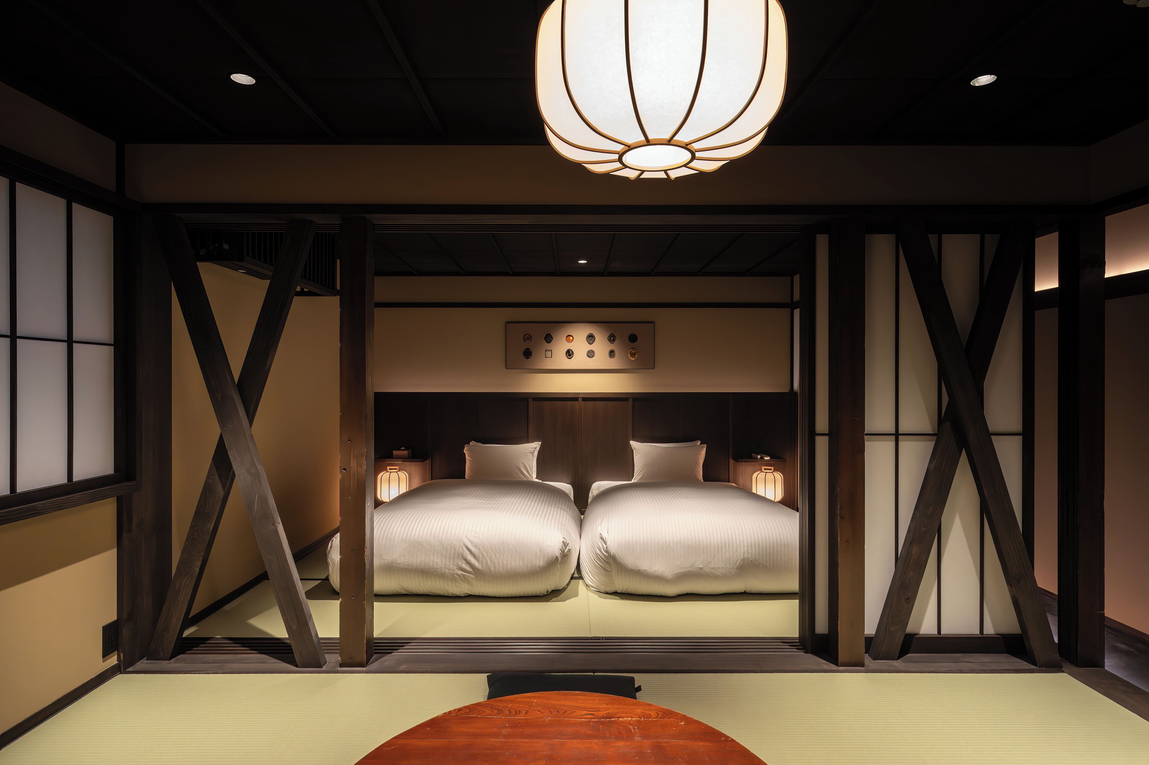 A traditional Japanese-style room with tatami flooring, a low wooden bed frame, and a hanging light fixture.