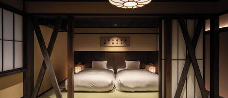 A traditional Japanese-style room with tatami flooring, a low wooden bed frame, and a hanging light fixture.