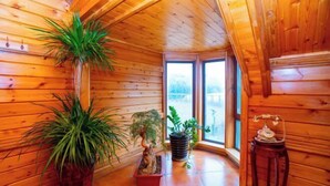 Interior de madera con plantas en macetas, un teléfono y vistas a través de un ventanal.