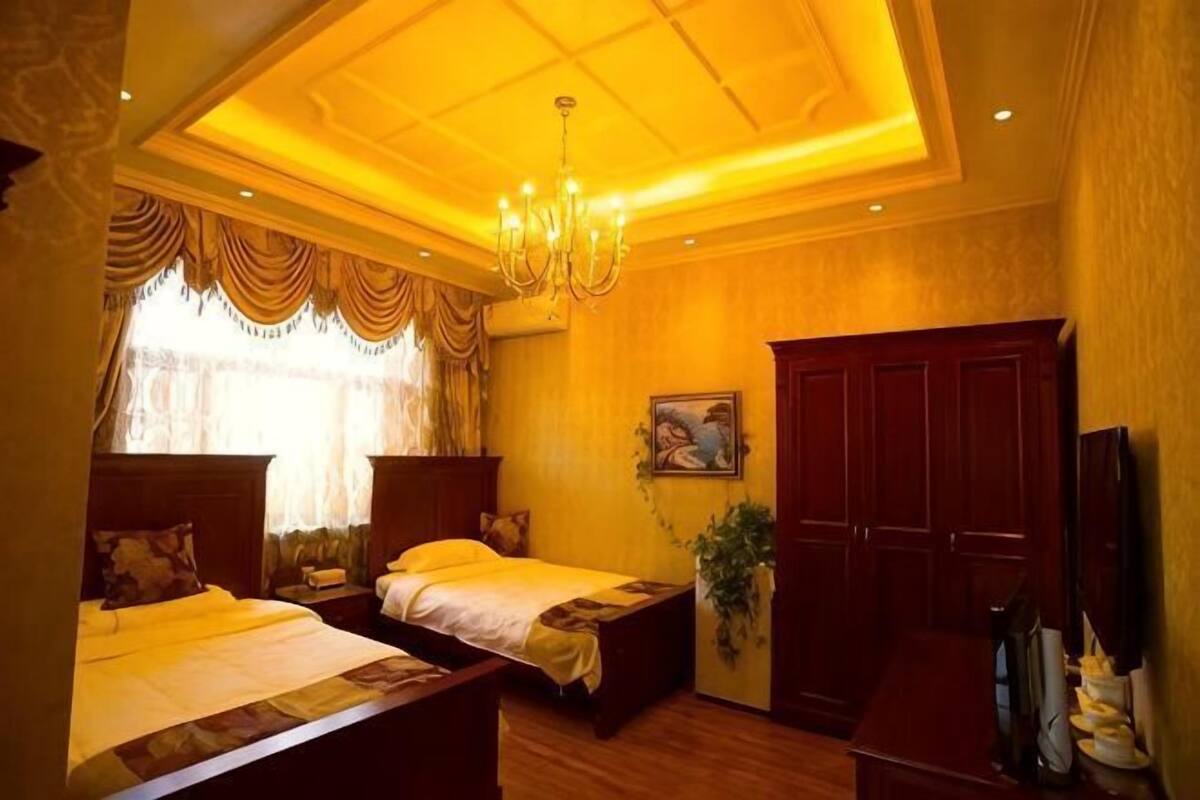 Een hotelkamer met twee bedden, een kroonluchter, een schilderij en een kledingkast.