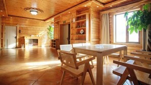 Un interior de madera con una mesa de comedor, sillas, estantes y una chimenea.