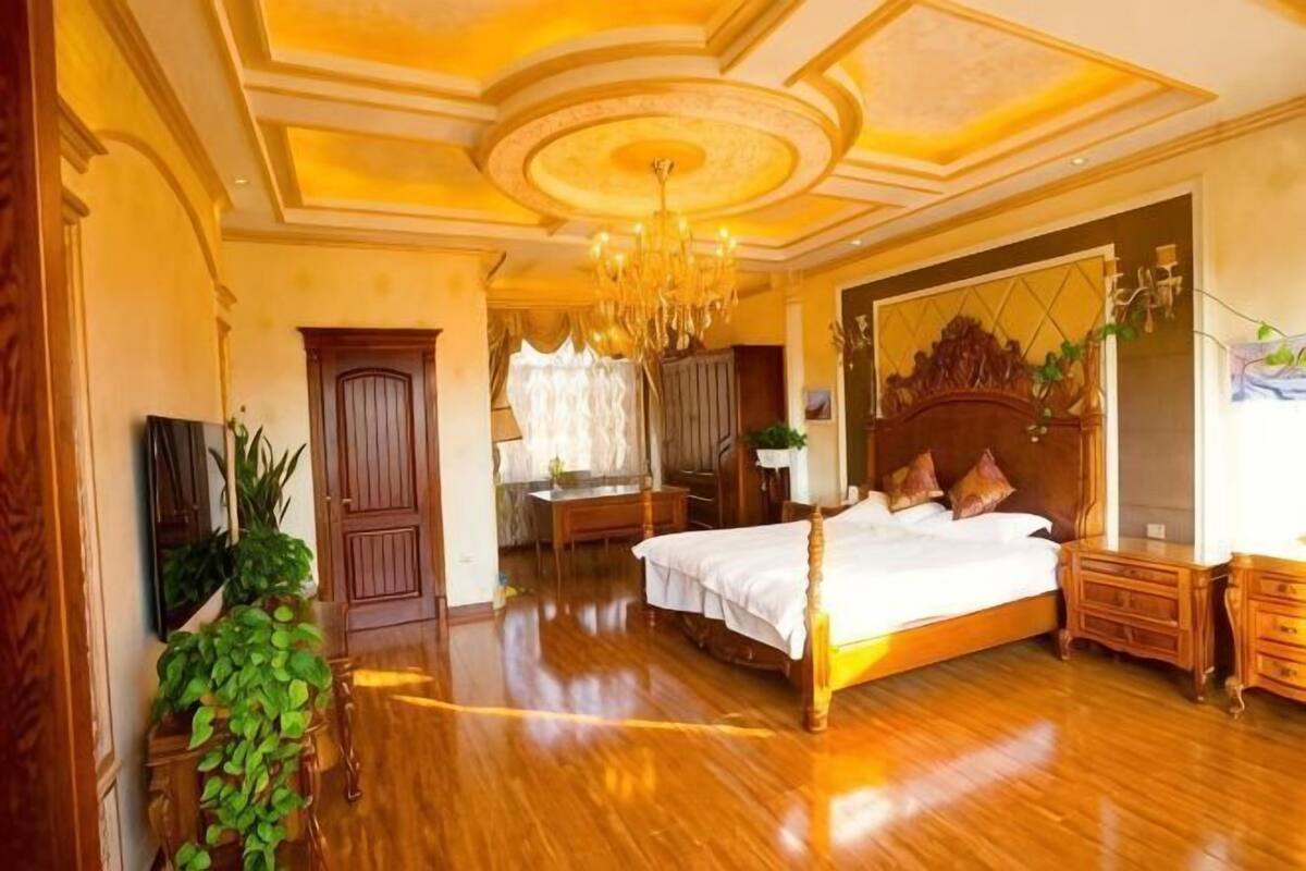 Een ruime slaapkamer met een groot bed, houten meubels en een kroonluchter.