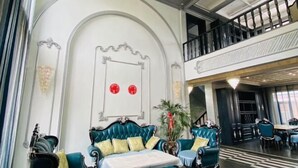 Un vestíbulo espacioso con techo alto, un balcón y una zona de estar con sofá y sillones.