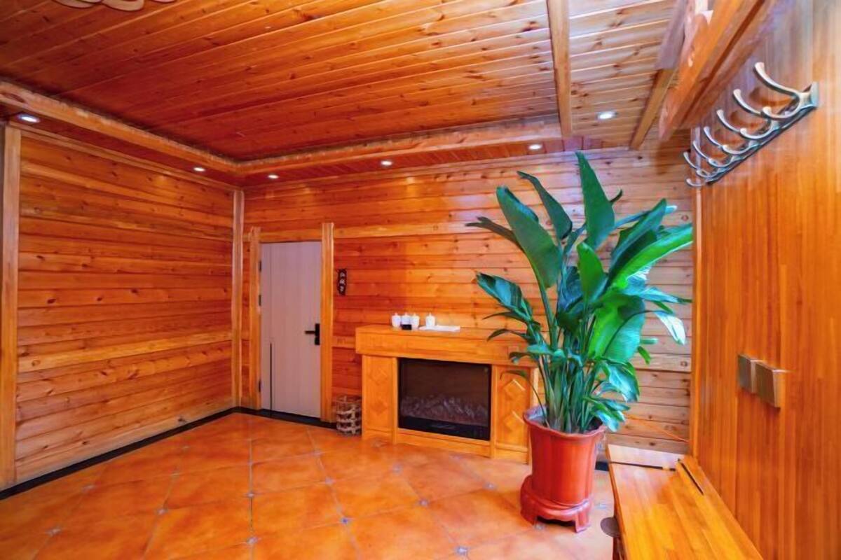 Een houten interieur met een open haard, een bankje en een potplant.