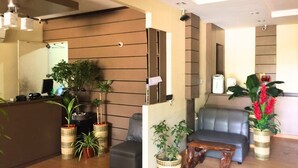 A modern reception area with a sofa, a wooden coffee table, and potted plants. - Pacific Palm Suites Davao powered by Cocotel (Davao)