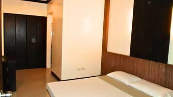 Una habitación de hotel con cama, armario y espejo.