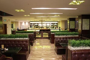 Un restaurant avec des banquettes et des tables, un bar central et un lustre.