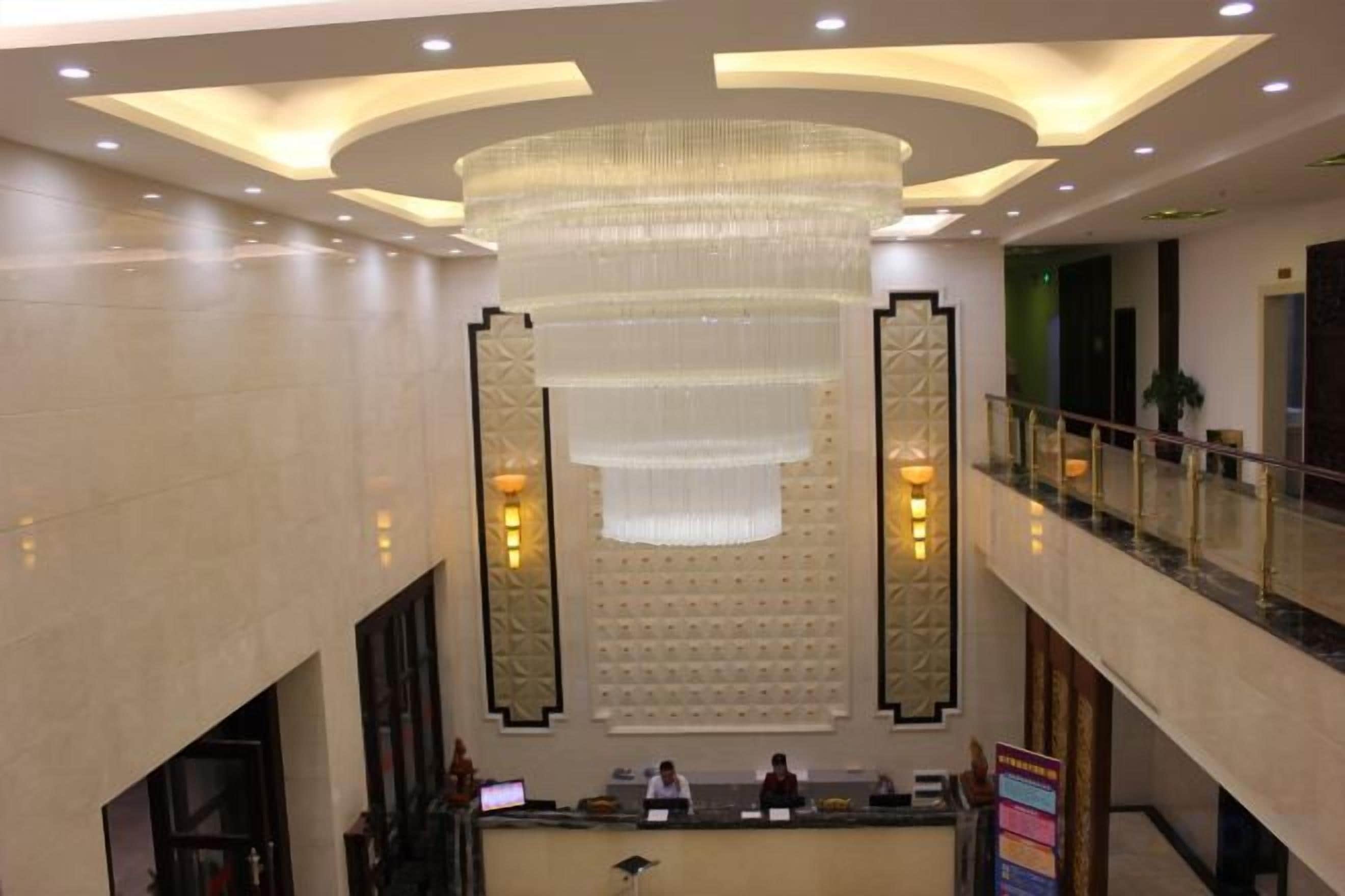 A lobby with a reception desk, a large chandelier, and a glass railing.