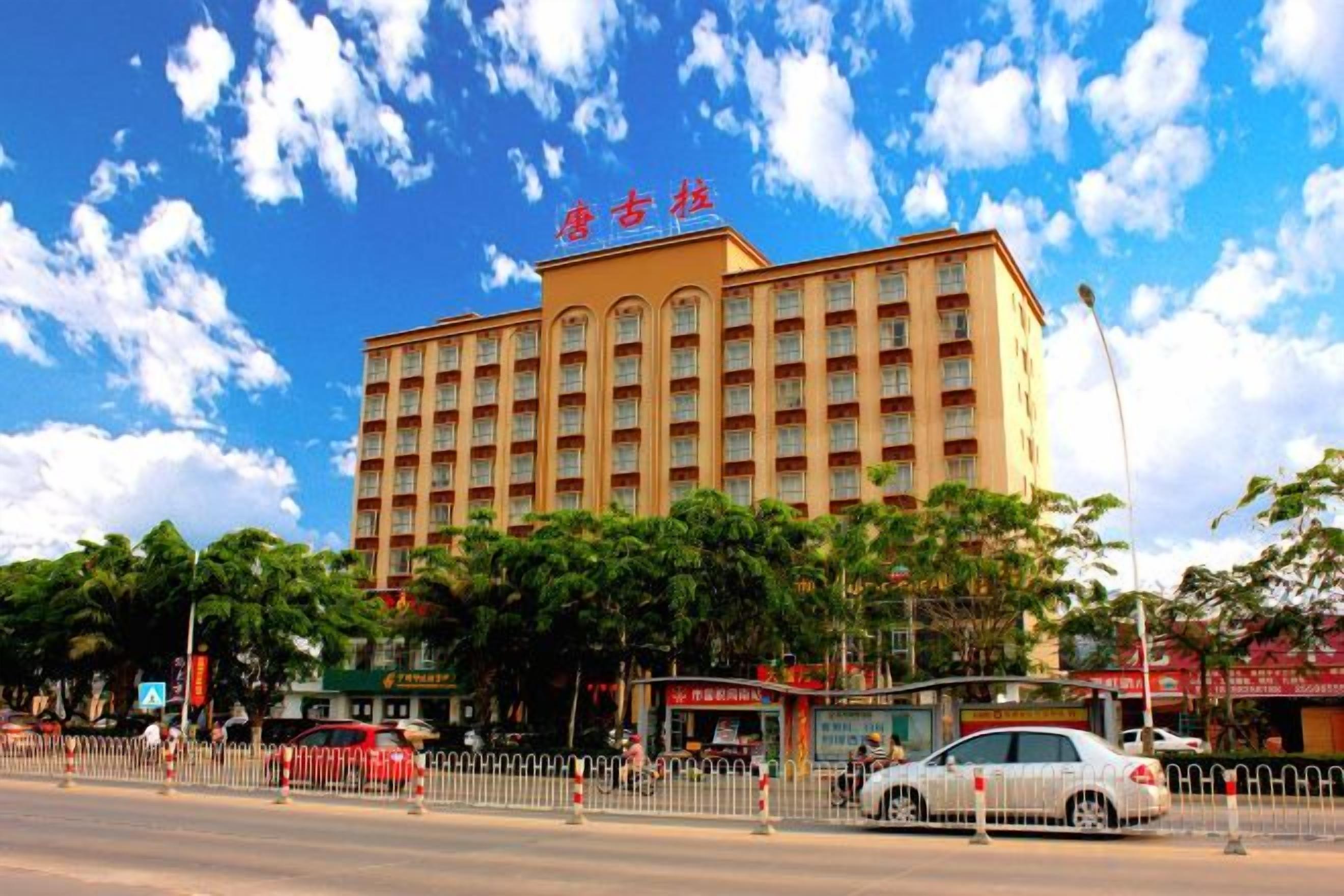 A multi-story hotel with a prominent entrance, surrounded by trees and a clear sky.