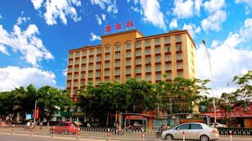 A multi-story hotel with a prominent entrance, surrounded by trees and a clear sky.
