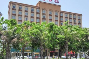 Un hotel de varios pisos con una entrada central, rodeado de árboles.