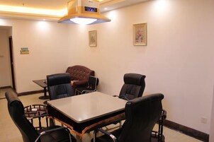 Un salón de conferencias con una mesa, sillas, un reloj y cuadros en la pared.